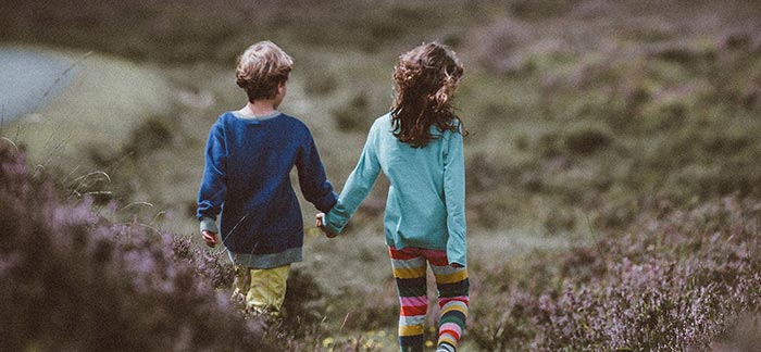 Image of two young girls walking holding hands in a field for Quotacy blog Two Families Living with the Unexpected.