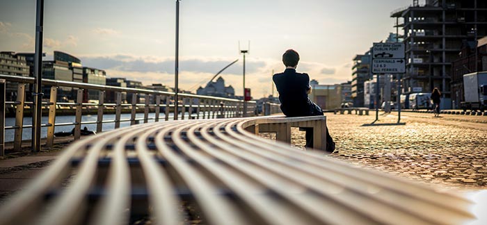 Image of person sitting alone on a bench at a harbor for Quotacy blog I’m Unemployed. Can I Get Life Insurance?