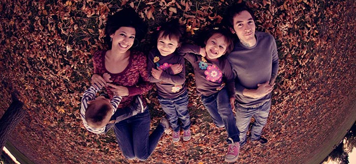 Image of happy family laying in autumn leaves together for Quotacy blog Talking to Your Family About Your Life Insurance.