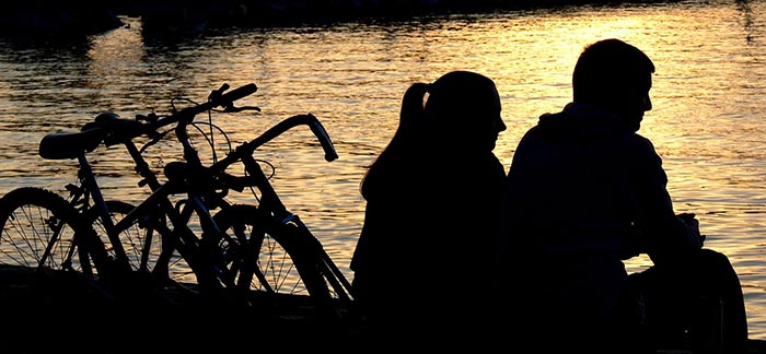 Image of couple with bikes sitting at a lake at sunset for Quotacy blog I Don’t Have Children Do I Still Need Life Insurance?
