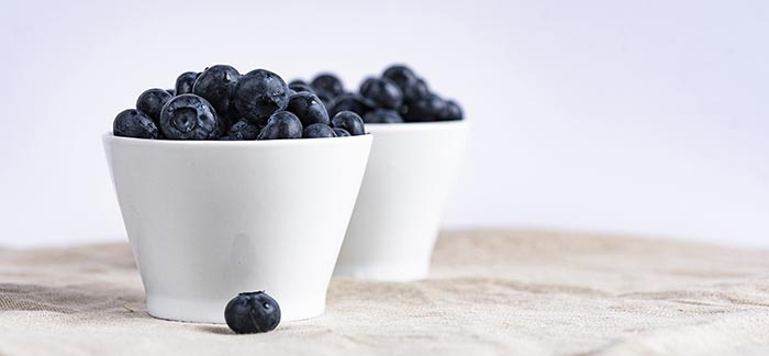Image of two bowls of blueberries sitting on a table for Quotacy blog 5 Simple Tips to Eat for Better Health.