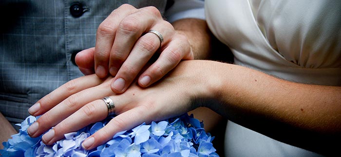 Image of young married couple showing off their wedding rings for Quotacy blog Financial Benefits of Getting Married.