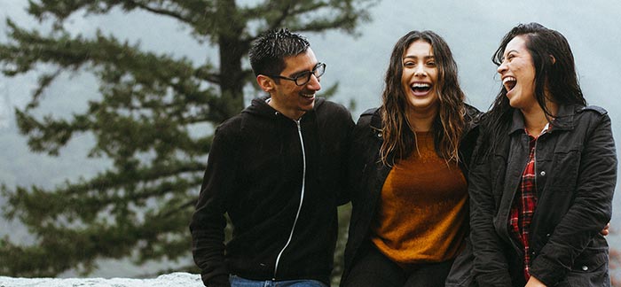 Image of Hispanic siblings laughing together outside in the rain for Quotacy blog Hispanic Families and Life Insurance.