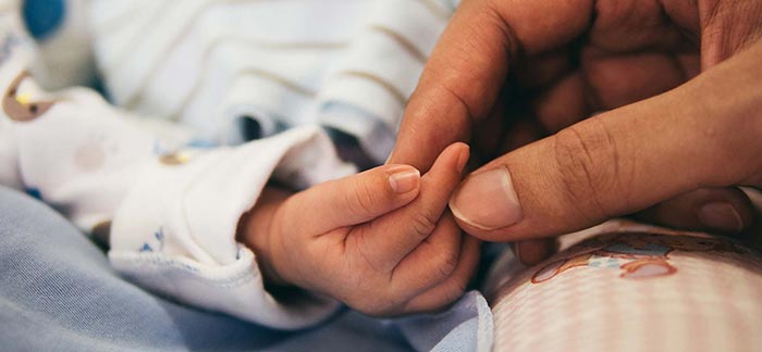 adult holding newborn hand