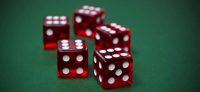 five rolled dice showing the number six on a poker table