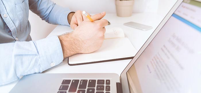 Image of person looking at computer laptop and taking notes for Quotacy blog Your Annual Financial Checkup.