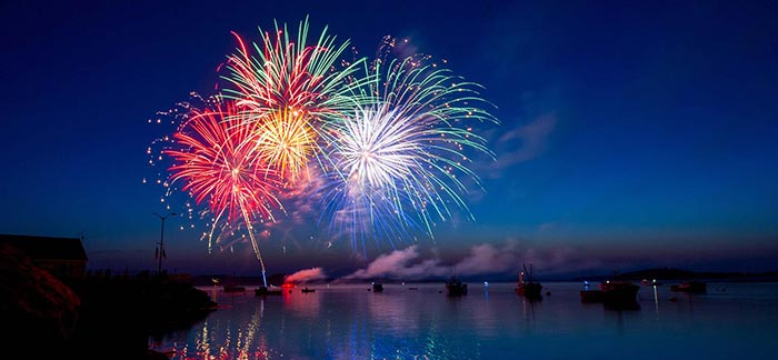 Image of multicolored fireworks exploding in the sky over a lake for Quotacy blog Life Insurance: Your New Year's Resolution.