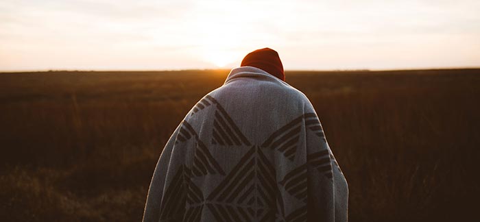 Image of person standing outside at sunrise wrapped in a blanket for Quotacy blog Life Insurance & Alcohol Use: Buyer's Guide