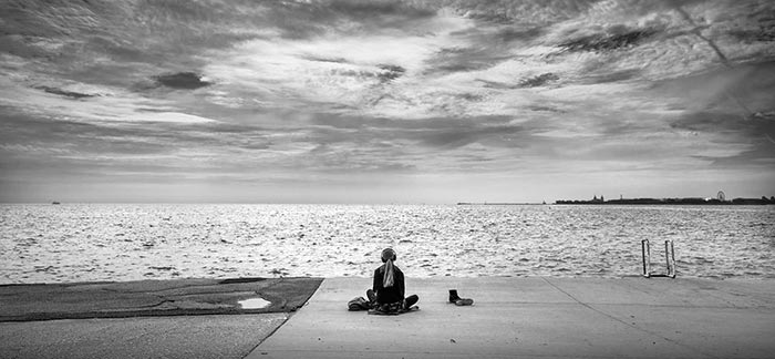 Image of woman with headphones relaxing in front of the ocean for Quotacy blog 10 Ways to Reduce Stress and Find Relaxation.