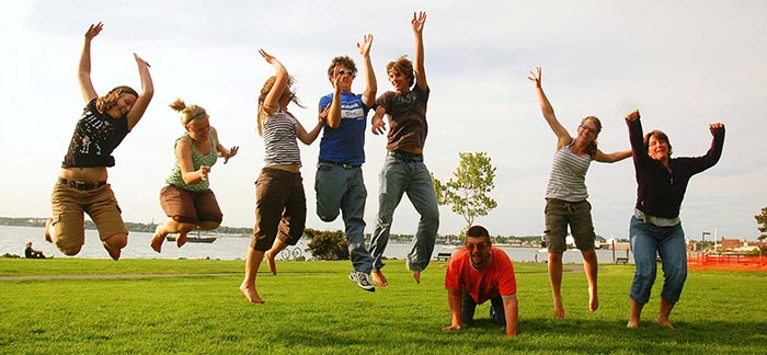 Image of friends and family jumping happily in the air in front of a lake for Quotacy blog Does Everyone Need Life Insurance?