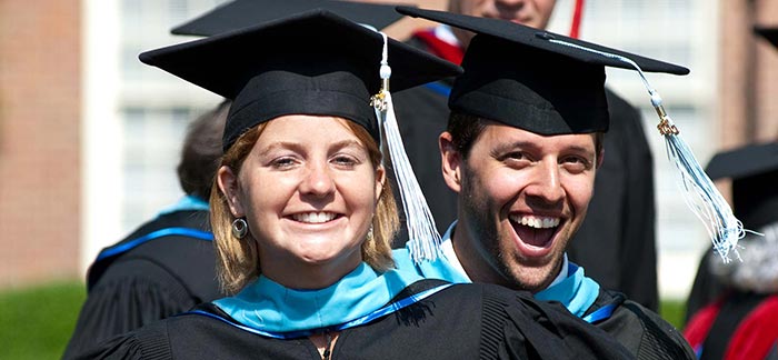 Image of two college graduates with smiling faces in their cap and gown.