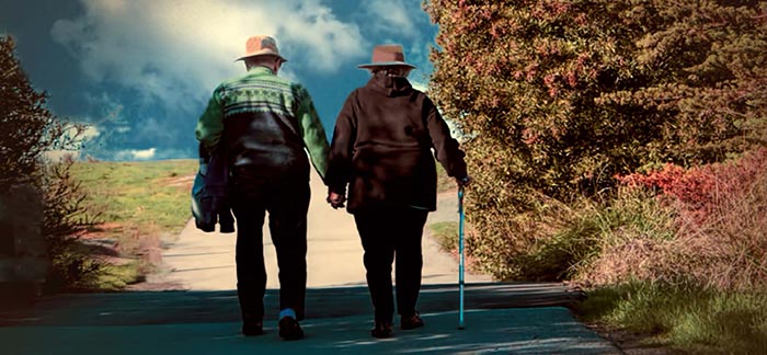 senior couple walking outdoors on hiking trail holding hands