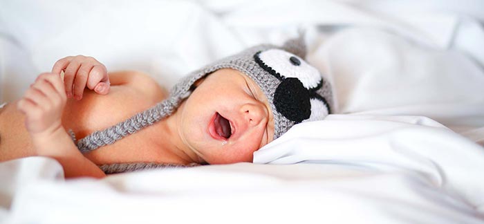 Image of sleeping newborn baby wearing a knitted animal hat for Quotacy blog Reasons Young Families Choose Term Insurance.