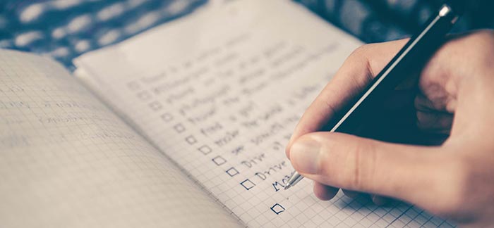 Image of person writing a checklist in a notebook for Quotacy blog A Basic Estate Planning Checklist.