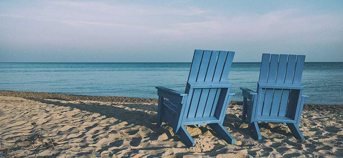 Image of two empty beach chairs in front of the ocean for Quotacy blog Financially Planning for the Four Stages of Retirement