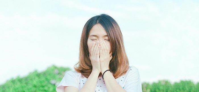 Image of a woman outside sneezing for Quotacy blog Time to Stay Healthy: Your Cold and Flu Survival Guide.