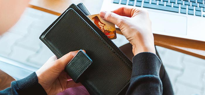 Image of woman opening wallet at desk to retrieve her credit card