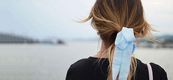 Image of woman wearing a blue ribbon standing on a beach