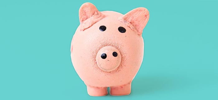 Image of pink ceramic piggy bank against teal background for Quotacy blog How Can I Reduce My Debt?