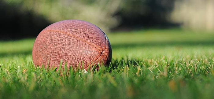 Image of a football on the grass for Quotacy blog Super Bowl Babies (Why You Should Buy Life Insurance Before Your Pregnancy)
