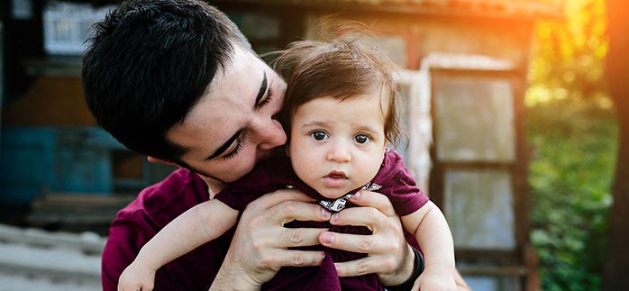 Image of dad holding and kissing baby for Quotacy blog Life Insurance Child Rider That Requires No Medical Information.