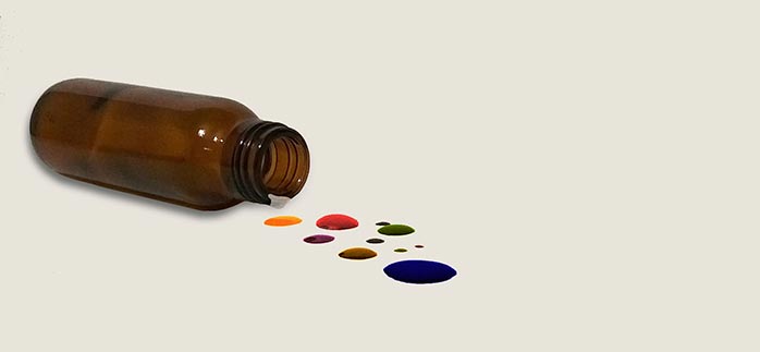 Image of amber bottle with spilled multicolored liquid for Quotacy blog National Poison Prevention Week.