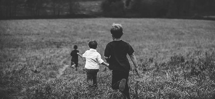 Image of three young boys running in a field outdoors for Quotacy blog What Is a Life Insurance Contingent Beneficiary?