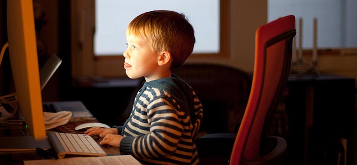 Image of child sitting & staring at computer screen for Quotacy blog Identity Theft: Not Just a Risk for Adults but Also Kids