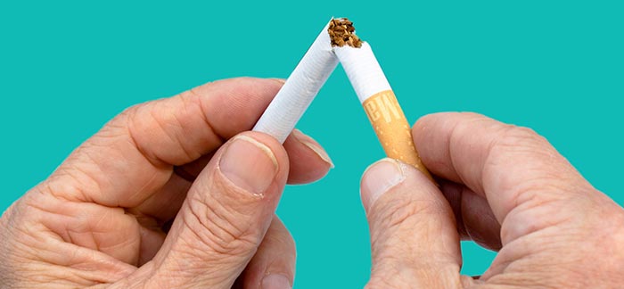 Image of two hands breaking a cigarette in half for Quotacy blog How Smoking Cessation Products Affect Life Insurance Rates