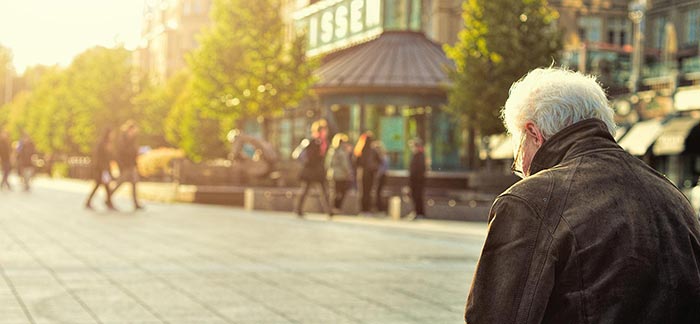 Image of elderly man sitting on bench downtown in a city