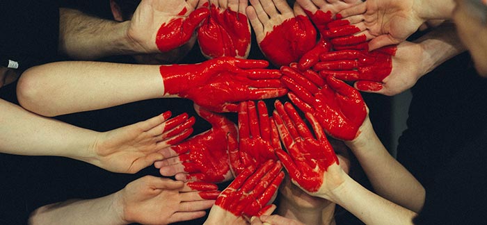 Image of several red painted hands held together to form a heart for Quotacy blog: Blood Cancers and Buying Life Insurance.