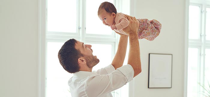 Image of stay-at-home dad holding baby in the air for Quotacy blog: Life Insurance for a Stay-at-Home Parent.