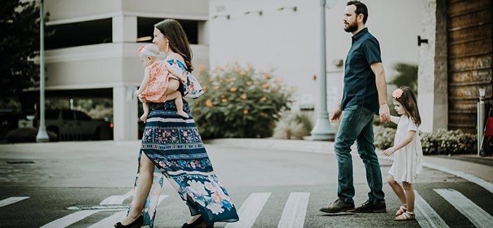 Image of young family of four walking on a crosswalk