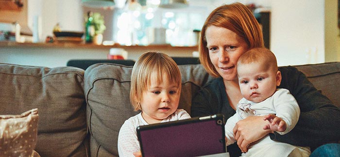 Image of mother and two young children looking at iPad