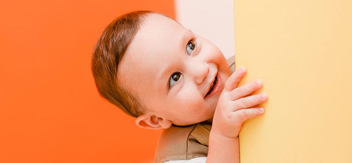 Image of smiling toddler peeking around wall for Quotacy blog: What if I Can’t Pay My Term Life Insurance Premiums on Time?