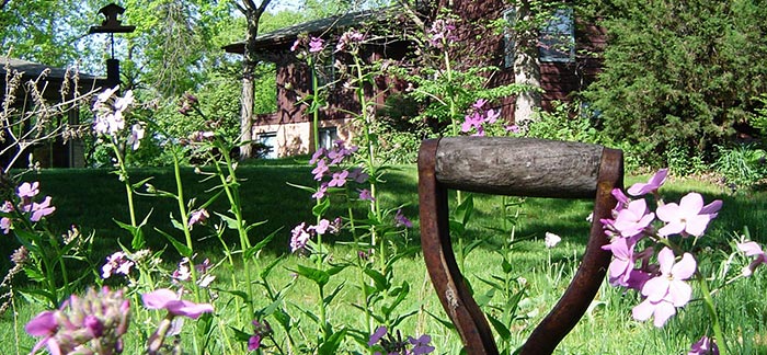 Image of flower garden with shovel in front of a cabin for Quotacy blog: What Is the Best Burial Insurance.