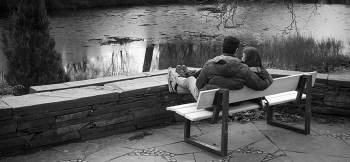 Image of couple sitting on a bench in a park looking at a pond for Quotacy blog Estate Planning 101 for Couples.