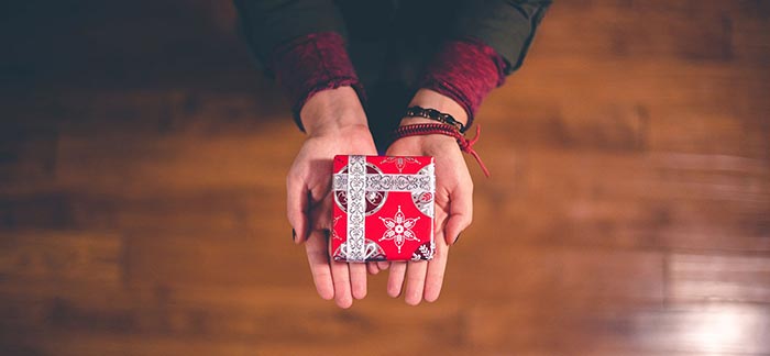 Image of woman's hands holding holiday gift for Quotacy blog: Holiday Gift Ideas That Show You Care.