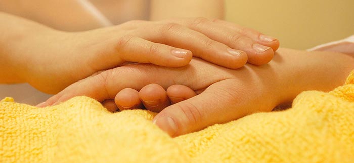 Image of caregiver holding the hand of a loved one for Quotacy blog The Importance of Having a Healthcare Power of Attorney.