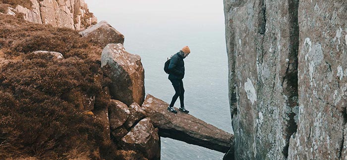 Man walking across stone ledge for Quotacy blog What Are the Life Insurance Risk Factors?