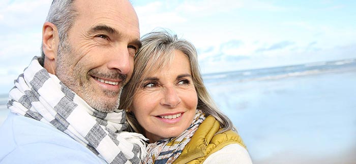 Mature couple embracing by a beach for Quotacy blog Financial Opportunities as You Age