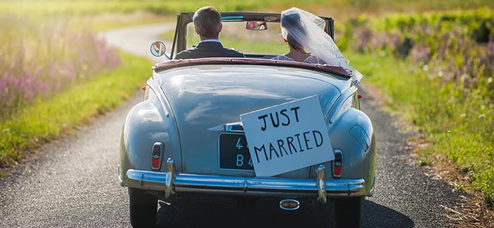 Newlyweds driving in a car with a Just Married sign for Quotacy blog What Newlyweds Need to Know About Term Life Insurance