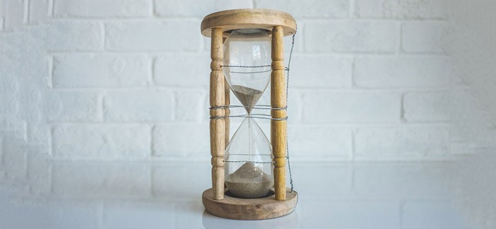 Image of hourglass with sand falling with a white brick wall background for Quotacy blog How Do Term Conversions Work?