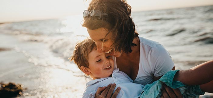 Mom holding her young son in her arms on the beach