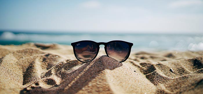 sunglasses on beach for Quotacy blog Budget Tips to Help You Save for Spring Break Vacation