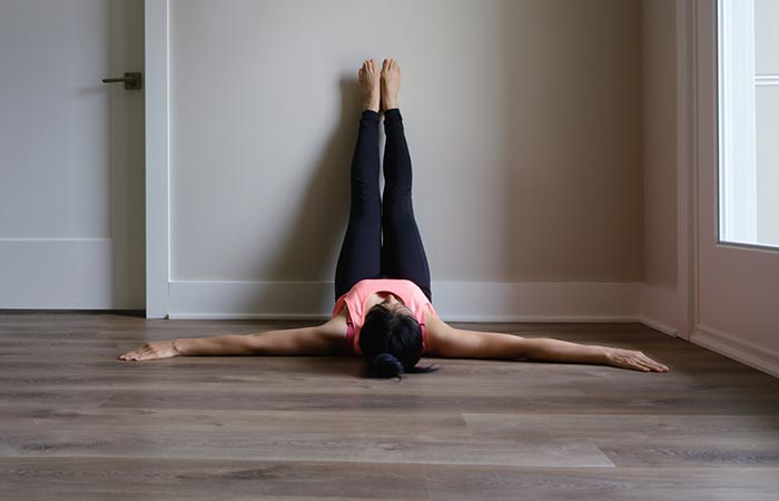 woman doing yoga laying flat with legs up the wall