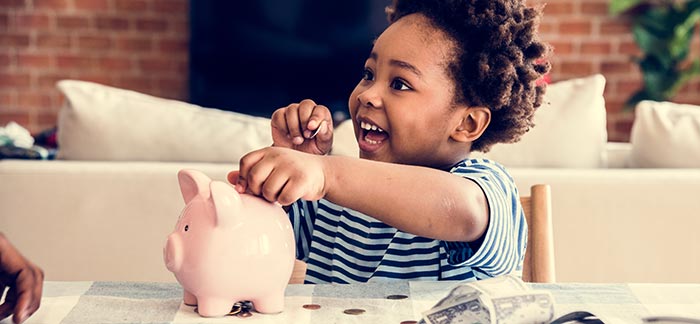 male child putting coins in piggy bank