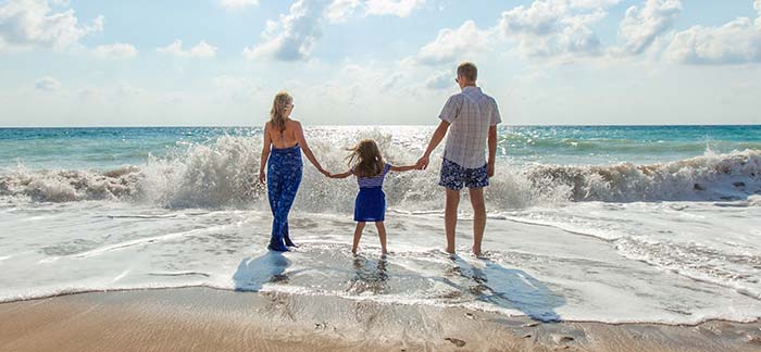 Mom Dad and daughter on a beach for the Quotacy landing page: A Guide to family life insurance. 