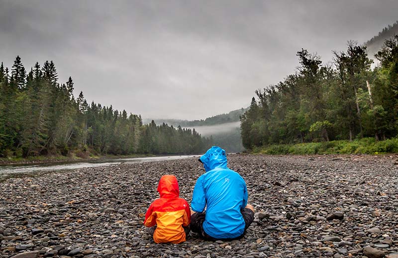 buying_a_life_insurance_child_rider Dad and son sitting on a rocky river bed looking at the water.