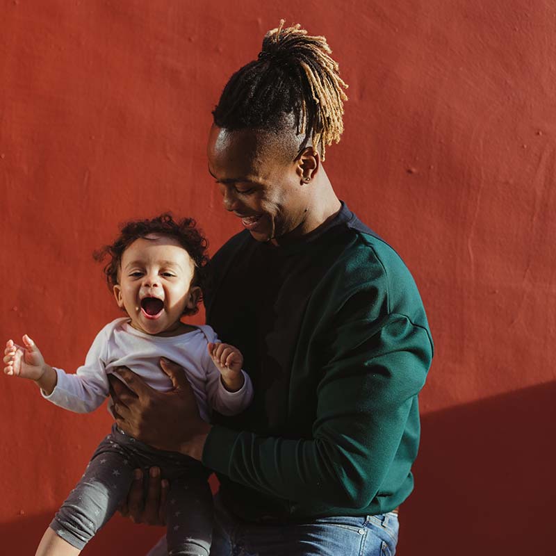 should_i_buy_life_insurance_on_my_child_3 Dad holding his daughter and bouncing her on his knee.